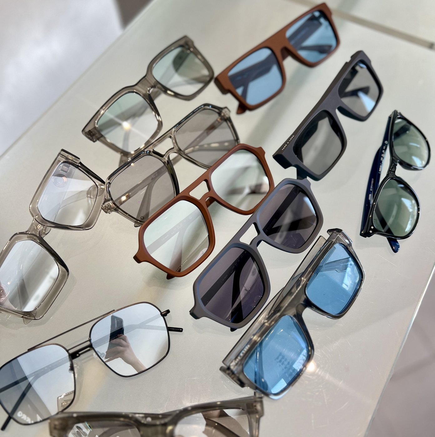 Colección de armazones recetados y anteojos de sol de Óptica Navarro dispuestos sobre el mostrador blanco